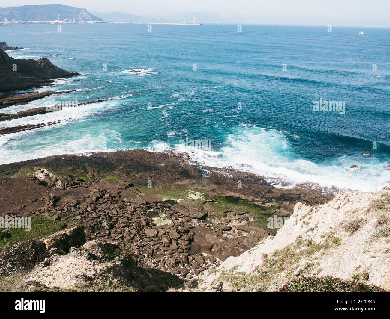 Zerklüftete Küstenlandschaft mit felsigen Klippen und azurblauem Wasser unter klarem Himmel. Stockfoto