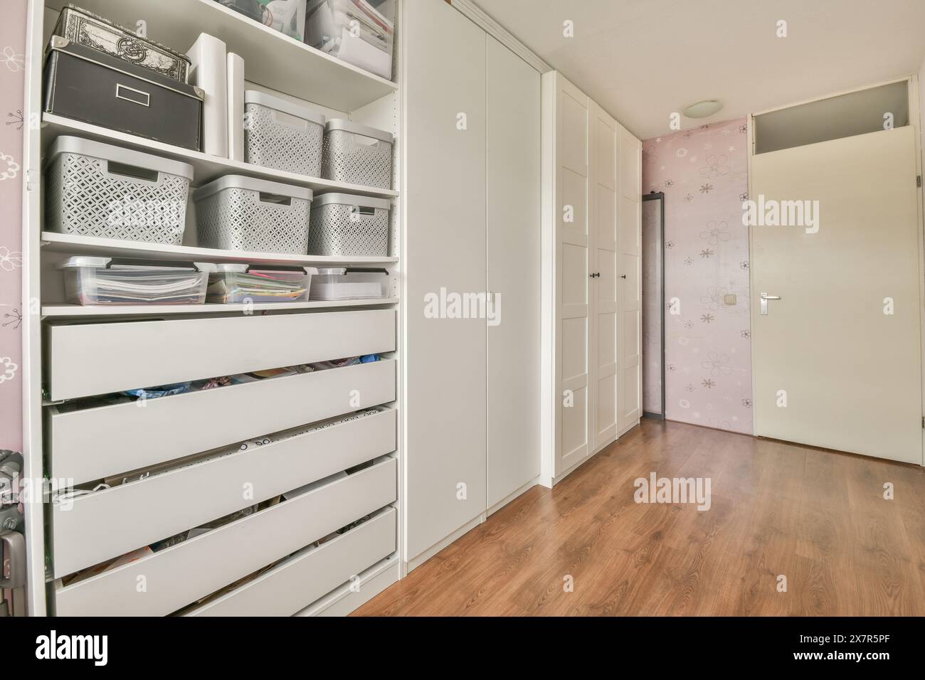 Ein organisierter Schrank mit mehreren Regalen und Schubladen mit Abstellkörben, Boxen und ordentlich angeordneten Gegenständen. Stockfoto