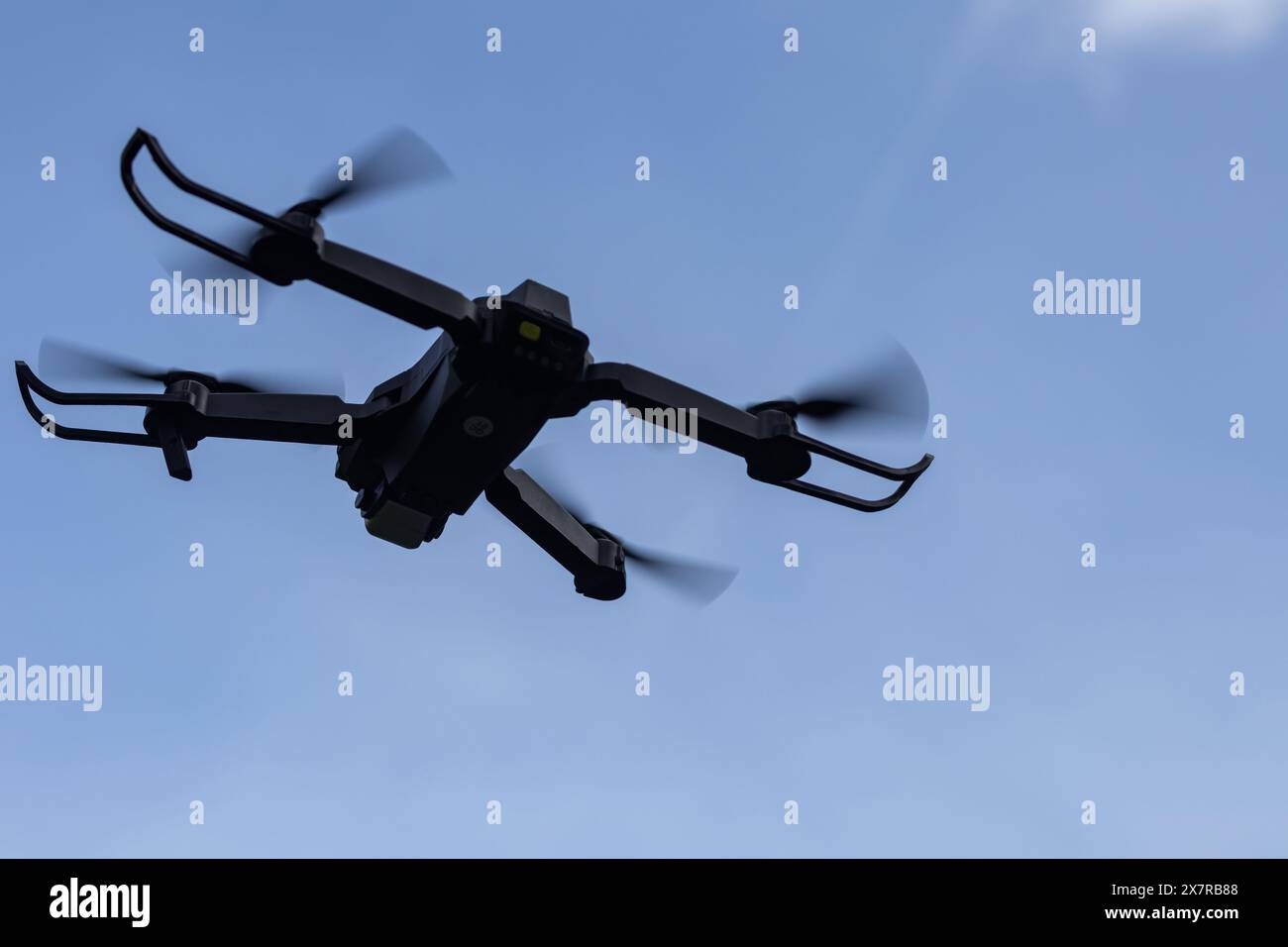 Drohne fliegt in der Luft in geringer Höhe gegen einen blauen Himmel. Drohne macht Fotos. Moderne neue Technologie. Fertiger Hintergrund mit Platz für Ihren Text. Stockfoto