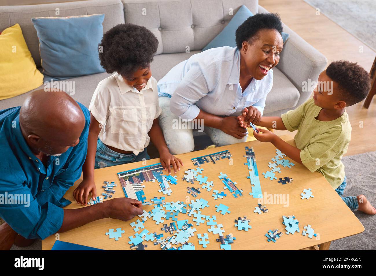 Großeltern Mit Enkelkindern Sitzen Zuhause Um Den Tisch Und Machen Gemeinsam Puzzle Stockfoto