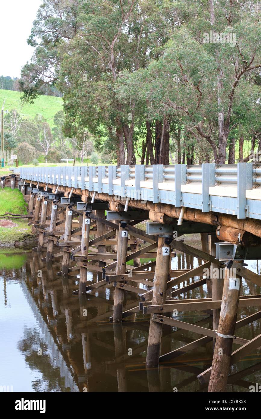 Ein vertikales Bild einer hölzernen Brücke über den Blackwood River mit Bäumen am Flussufer zwischen Balingup und Nannup im Südwesten von Western Australia. Stockfoto