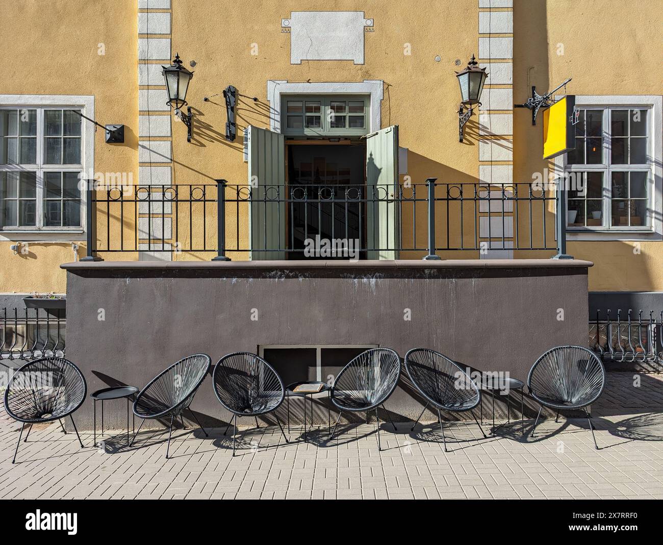 Korbstühle und kleine Tische in einem Straßencafé in der Altstadt von Riga, Lettland. Stockfoto