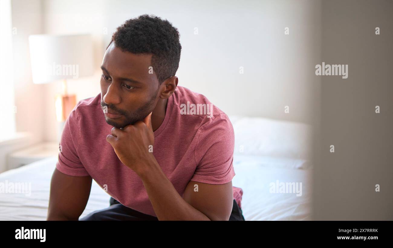 Unglücklicher Oder Depressiver Mann, Der Zu Hause Auf Dem Bett Sitzt Stockfoto