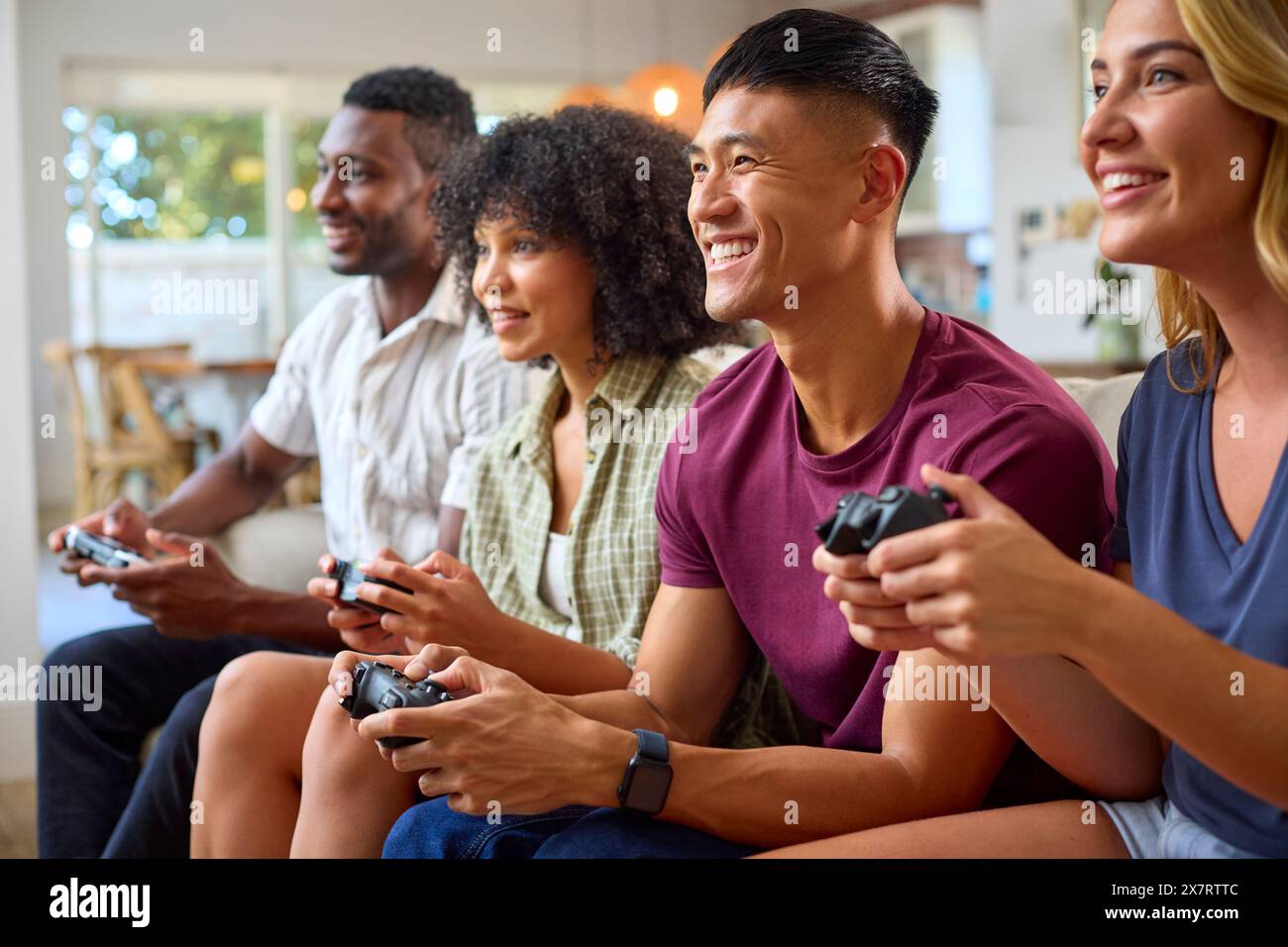Eine Gruppe Aufgeregter Multi-Racial-Freunde, Die Auf Sofa Sitzen Und Gemeinsam Computerspiele Spielen Stockfoto