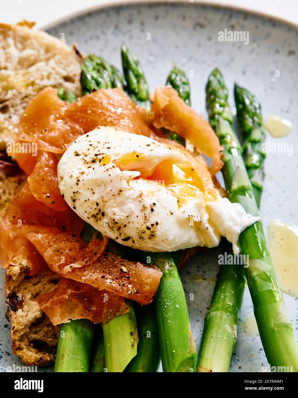 Geräucherter Lachs, pochiertes Ei auf gedämpftem Spargel auf Sauerteigbrot, Nahaufnahme Stockfoto