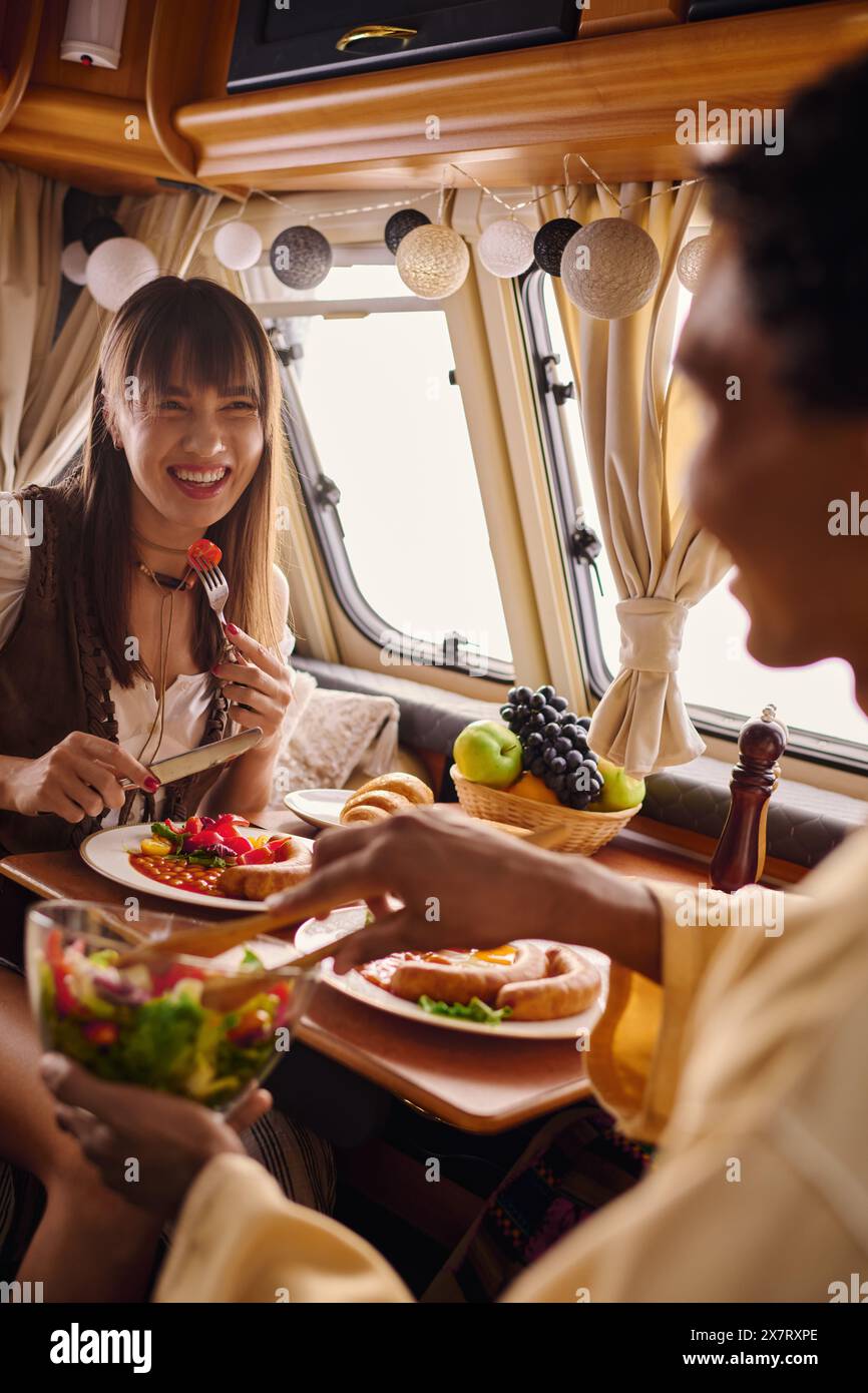 Eine vielfältige Gruppe von Freunden genießt eine gemeinsame Mahlzeit und Unterhaltung an einem Tisch voller Speisen. Stockfoto