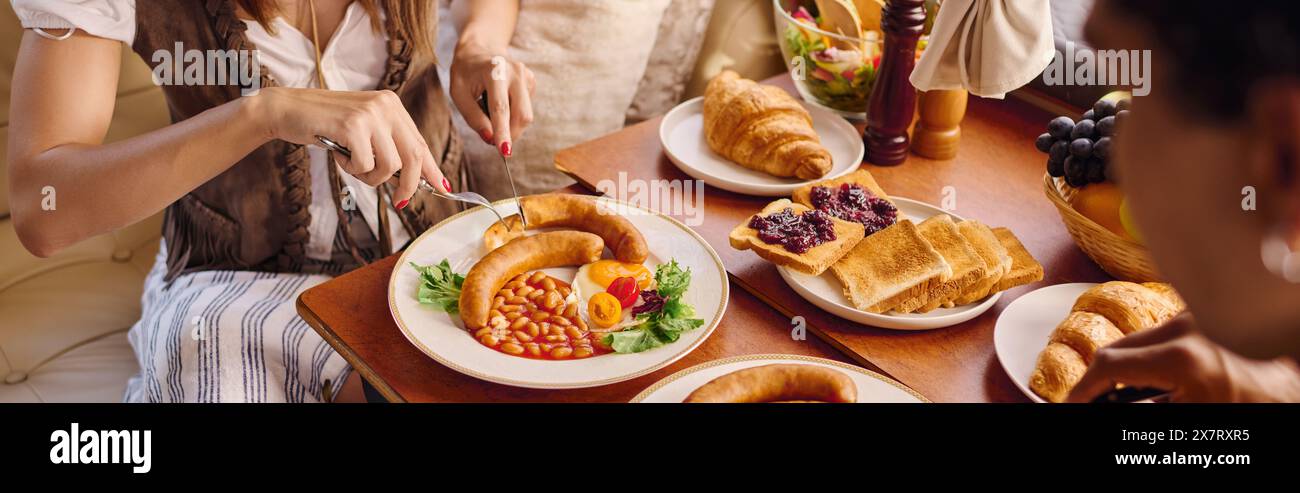 Ein vielseitiges Paar sitzt an einem Tisch und genießt Speisen in einer gemütlichen und gemeinschaftlichen Umgebung. Stockfoto