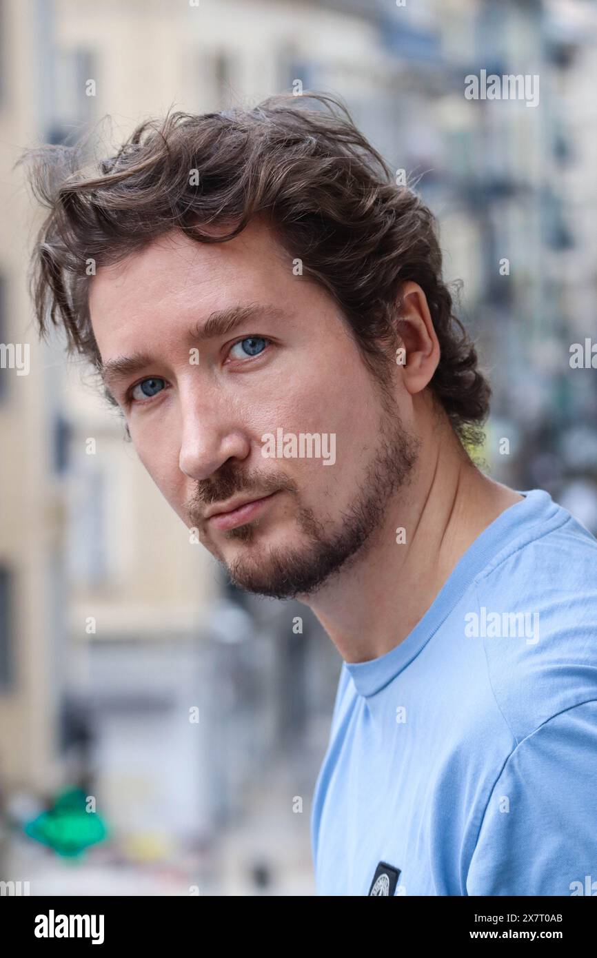 Hübscher junger Mann mit blauen Augen und lockigen, welligen Haaren Stockfoto