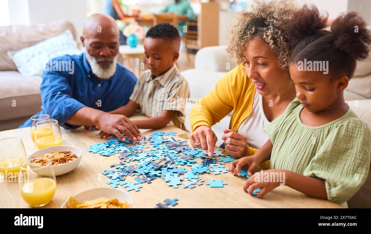 Großeltern Mit Enkelkindern Zu Hause Machen Puzzle Mit Eltern Im Hintergrund Stockfoto