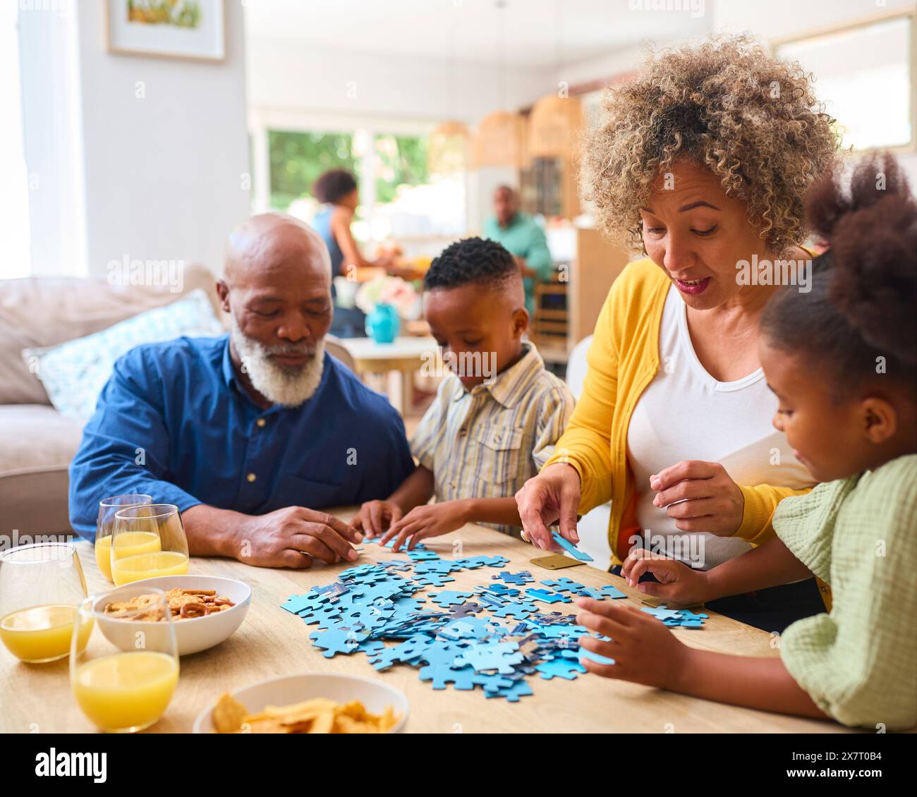 Großeltern Mit Enkelkindern Zu Hause Machen Puzzle Mit Eltern Im Hintergrund Stockfoto