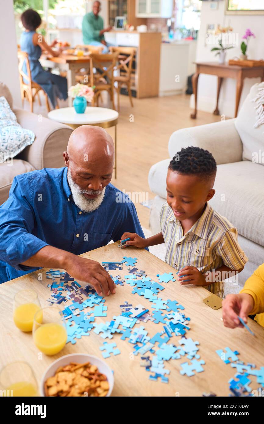 Großeltern Mit Enkelkindern Zu Hause Machen Puzzle Mit Eltern Im Hintergrund Stockfoto