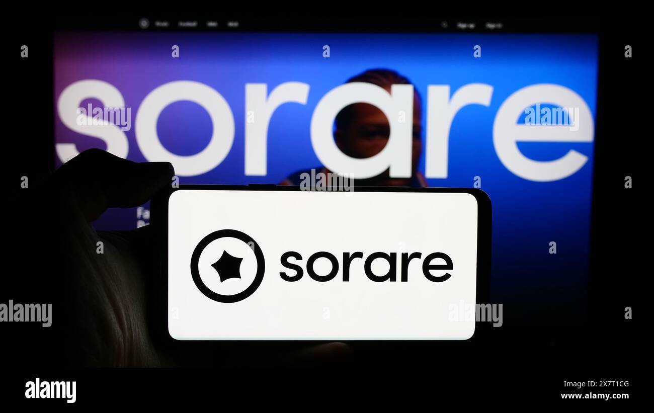 Person, die ein Handy mit dem Logo des französischen Krypto-Fantasy-Sportunternehmens Sorare SAS vor der Webseite hält. Schwerpunkt auf dem Display des Telefons. Stockfoto