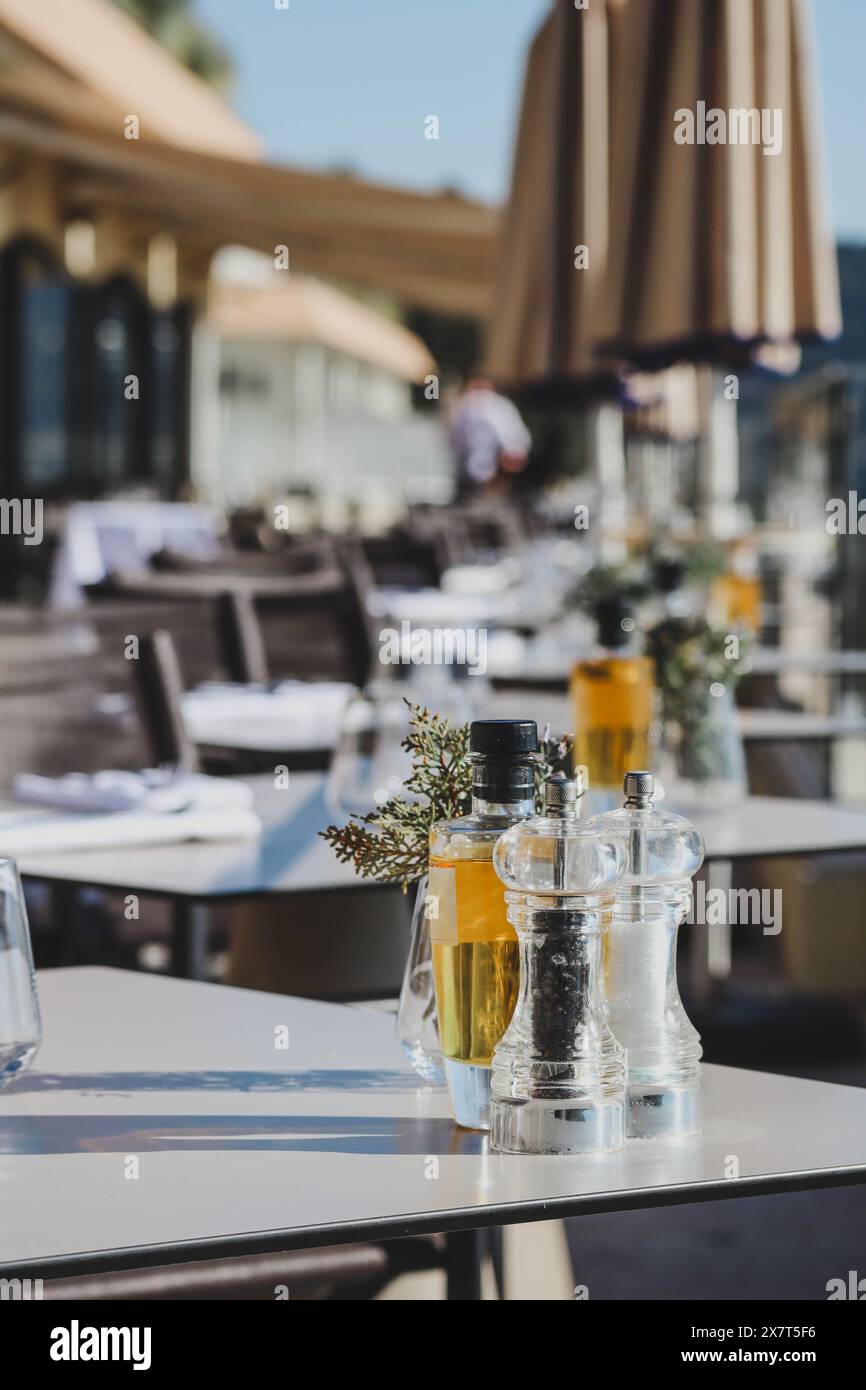 Nahaufnahme von Gegenständen auf einem Tisch in einem Restaurant: Wassergläser, Olivenzweig, Pfeffer, Salz und eine Flasche Öl Stockfoto