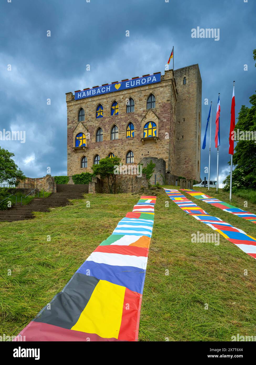 Das Hambacher Schloss mit europäischen Fahnen auf dem Rasen vor dem Schloss, transparent mit der Aufschrift Hambach Europa an der Schlossmauer und gelbe Sternen auf blauem Grund in den Fenstern. Vom 23. bis 26. Mai 2024 wird dort und in der Altstadt von Neustadt a.d. Weinstraße das fest der Demokratie feiern. Änd. 27. Mai 1832 kam bis zu 30,000 Menschen auf dem Hambacher Schlossberg zusammen, um für ein geeintes Deutschland, politische Grundrechte und ein solidarisches verbundenes Europa eintreten. Wegen des 1832 dort ausgerichteten Hambacher Festes gilt es neben der Frankfurter Paulskirche Stockfoto