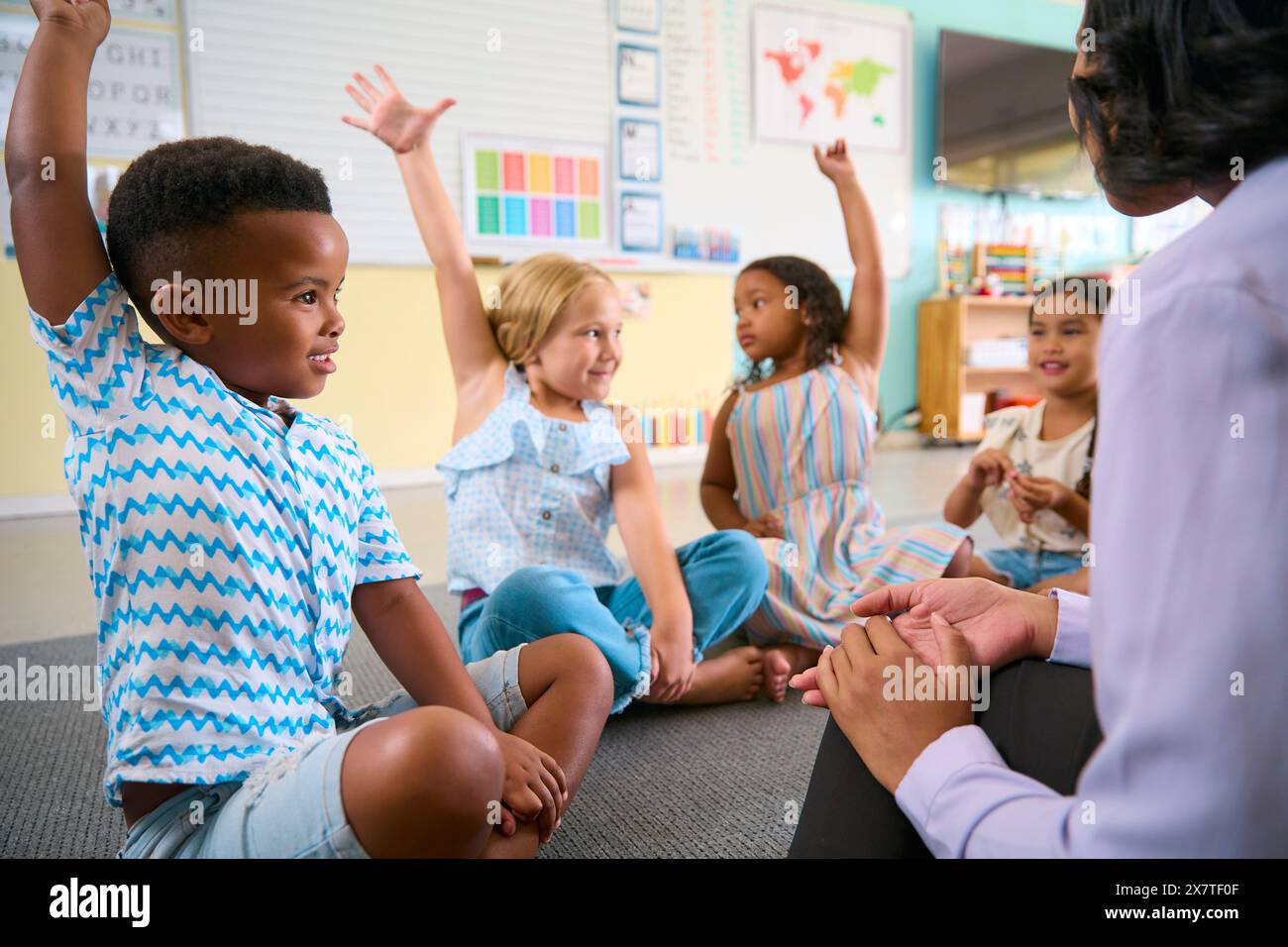 Klasse Von Primar- Oder Grundschulschülern, Die Die Hände Heben, Um Fragen Im Klassenzimmer Zu Beantworten Stockfoto