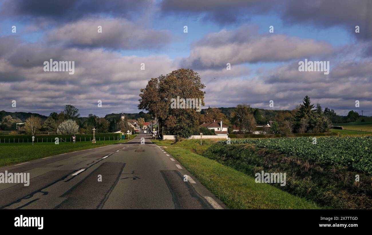 Französische ländliche Landschaft mit einer Landstraße und einem Dorf am Horizont irgendwo in Frankreich Stockfoto