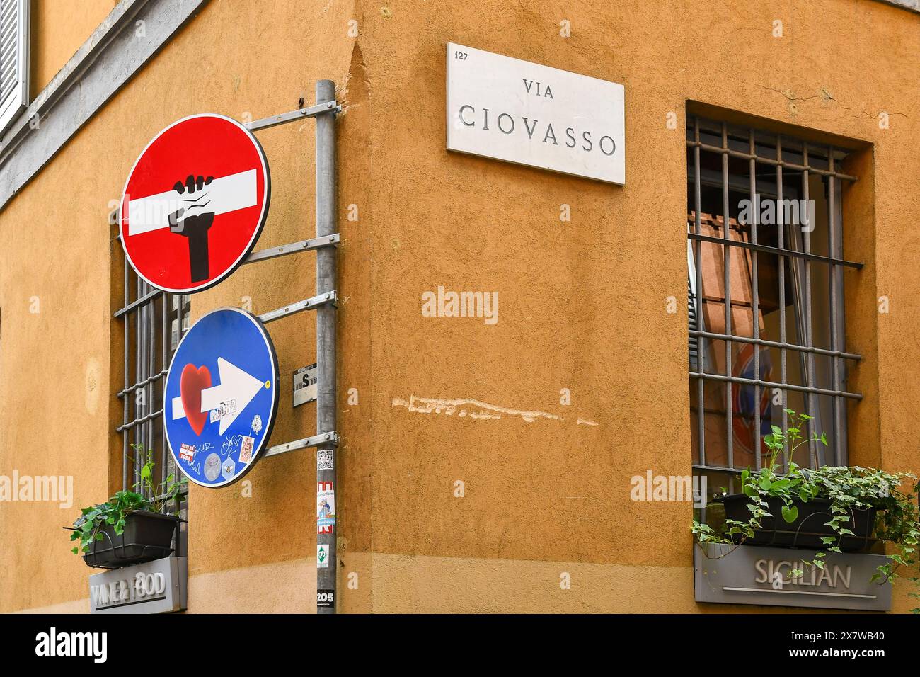 Straßenschilder wurden zu Straßenaufklebern von Clet Abraham, einem französischen Künstler, der seit 1990 in Italien tätig ist, in einem Gebäude im Stadtteil Brera in Mailand verwandelt Stockfoto