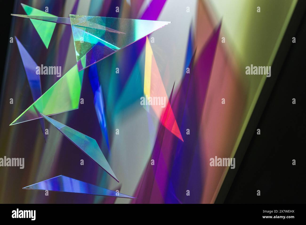Abstraktes Hintergrundfoto mit bunten transparenten Dreiecken, die helle Schatten auf die Wand werfen Stockfoto