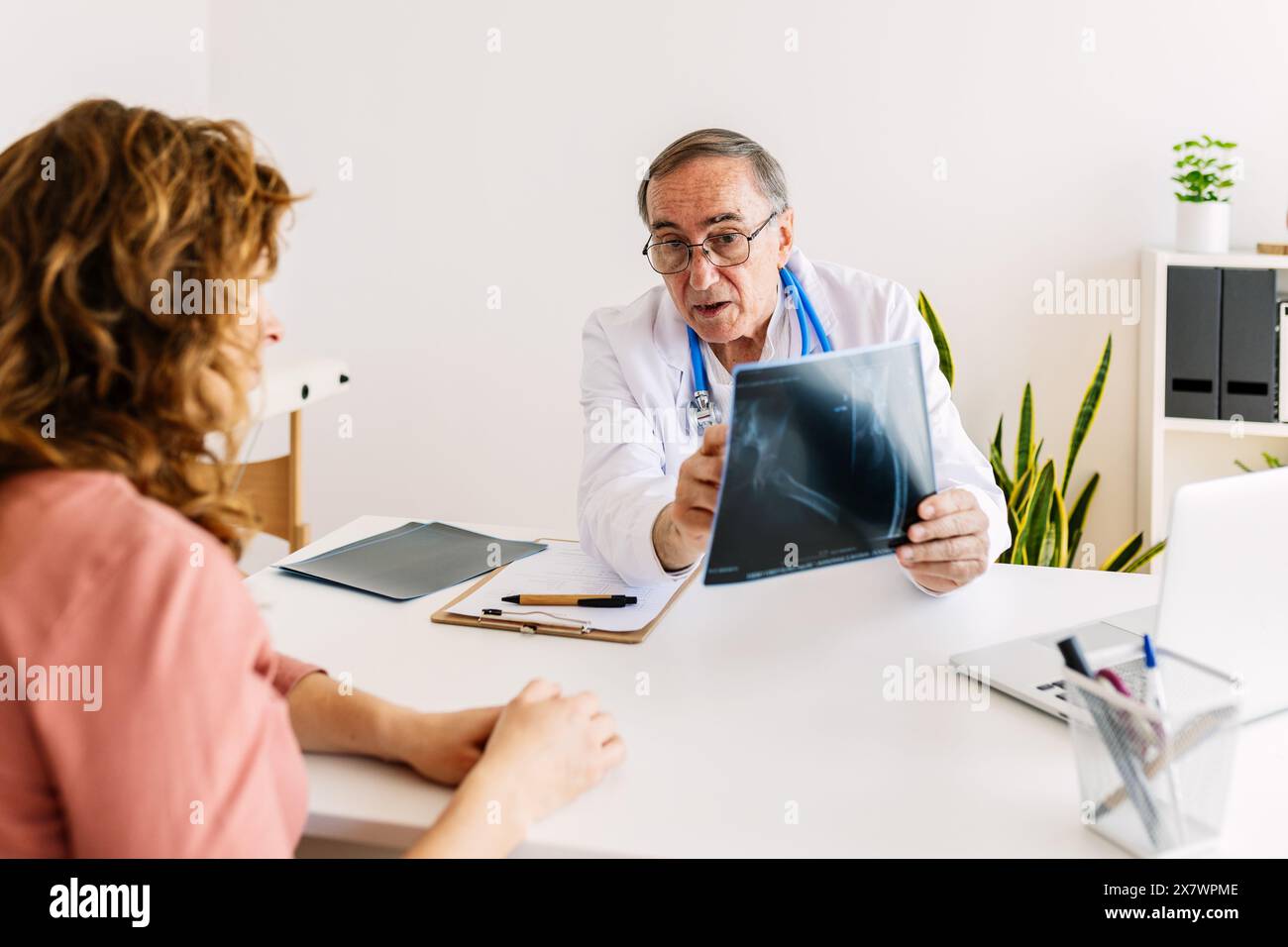 Männlicher Arzt, der mit weiblicher Patientin über medizinische Röntgenaufnahme im Krankenhaus diskutiert Stockfoto