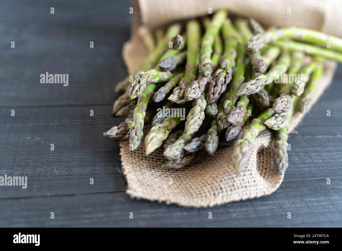 Nahaufnahme von frischem grünem Spargel vor dunklem Hintergrund in Tuch gewickelt Stockfoto