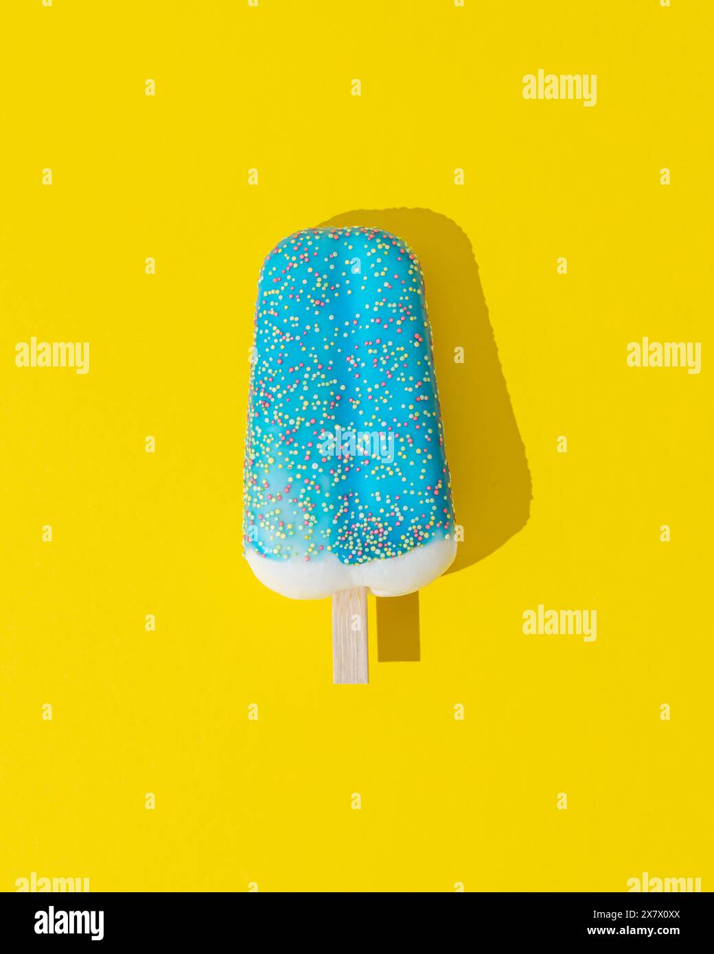 Blau glasiertes Eis-Eis auf gelbem Hintergrund. Minimales Sommerkonzept. Eisästhetik. Flache Lagen. Stockfoto