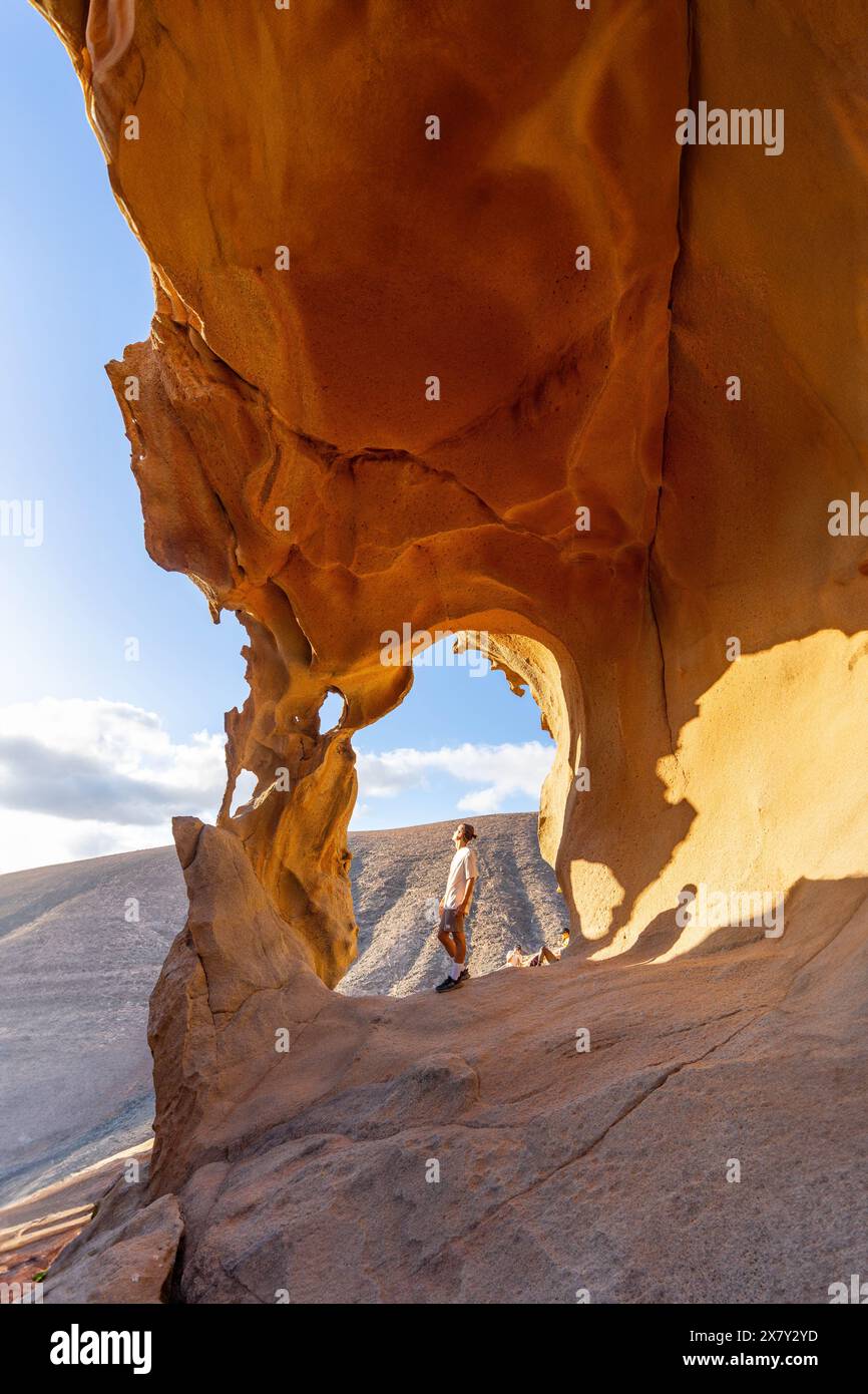Ein einsamer Wanderer bewundert die atemberaubenden, sonnendurchfluteten Felsformationen des Arco de Las Penitas und fängt das Wesen eines ruhigen, beeindruckenden Outdoor-Erlebnisses ein Stockfoto