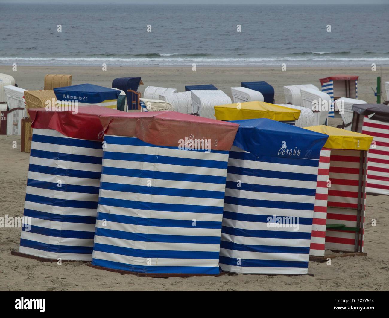 Reihe von bunten Liegestühlen mit Streifenmuster am Strand mit Blick aufs Meer, Liegestühle und Strandzelte am Meer unter bewölktem Himmel, Boa Stockfoto