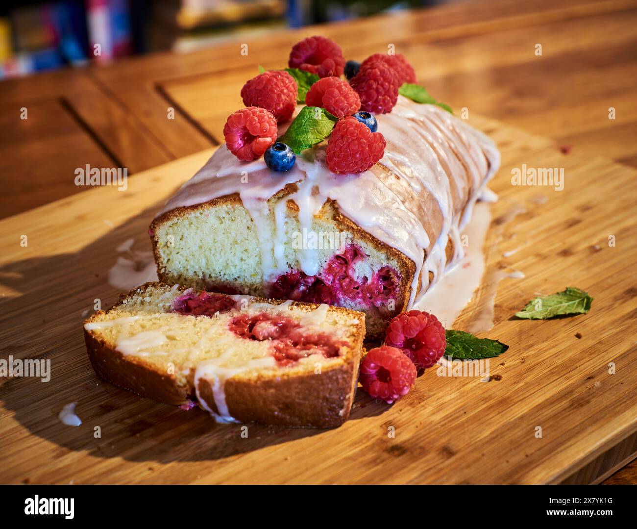 Weicher Himbeer-Fruchtkuchen oder Kuchen mit süßem geschmolzenem Zuckermantel und wilden Himbeeren auf einem Holztisch. Gezuckerter, weicher, warmer Plumcake, gebacken mit Beere Stockfoto