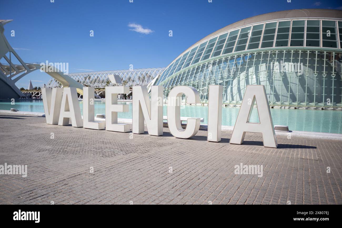 Modernes architektonisches Wahrzeichen in Valencia mit großen Buchstaben und reflektierendem Wasserpool unter klarem blauem Himmel Stockfoto