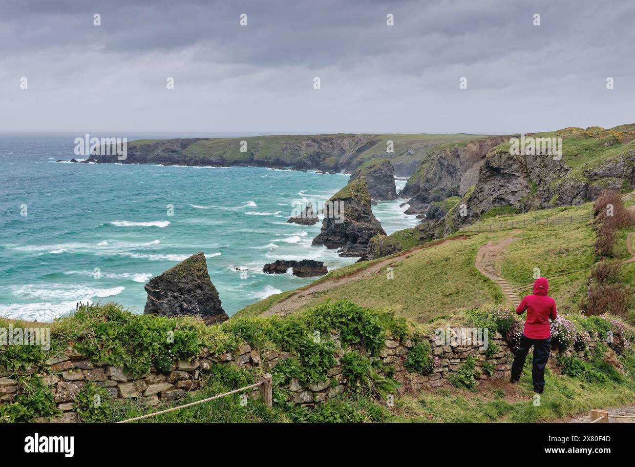 Rambler genießt an einem stürmischen Frühlingstag England Großbritannien den spektakulären Blick auf die Küste der Bedruthan Steps North Cornwall Stockfoto