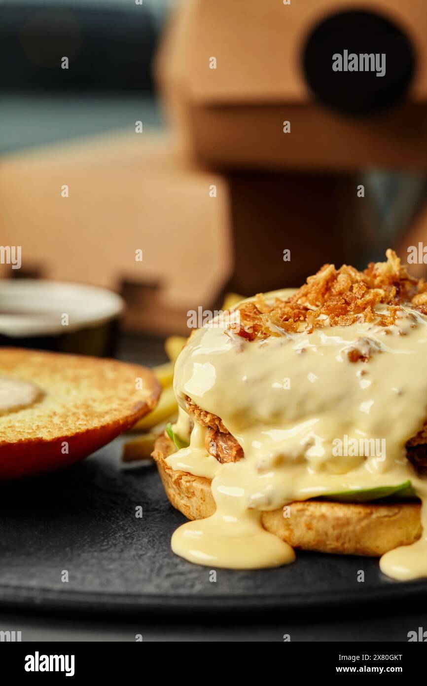 Offener Burger mit Käse-Sauce und knusprigen gebratenen Zwiebeln Stockfoto