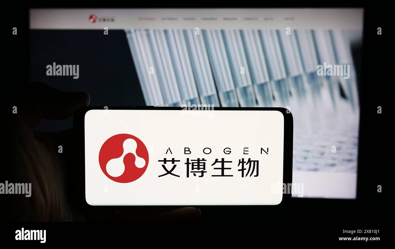 Person, die ein Mobiltelefon mit dem Logo des chinesischen Unternehmens Suzhou Abogen Biosciences Co. Ltd. Vor der Webseite des Unternehmens hält. Schwerpunkt auf dem Display des Telefons. Stockfoto