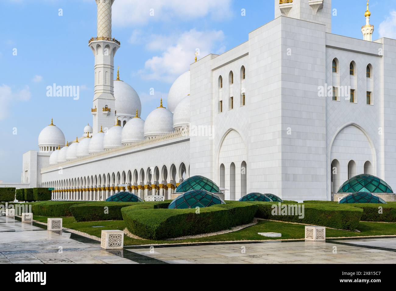 Die Scheich-Zayed-Moschee in Abu Dhabi zeigt zeitlose islamische Architektur, ihre reinweißen Kuppeln und Minarette heben sich vom klaren Blau ab Stockfoto
