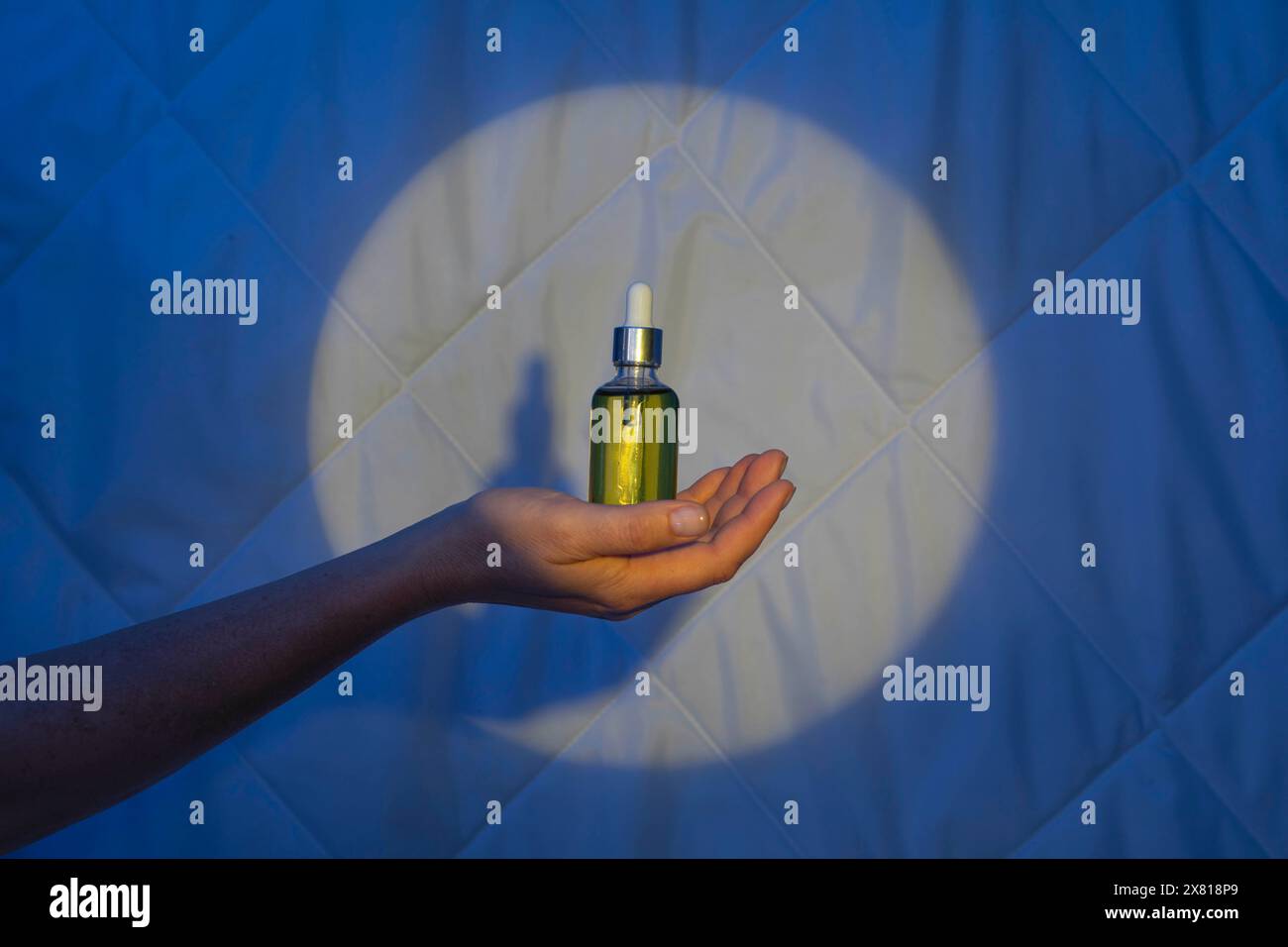 Frau Hand auf dem Hintergrund einer Decke im Licht des Mondes mit Tropfer mit Schlaföl. Schlaflosigkeit bekämpfen Stockfoto