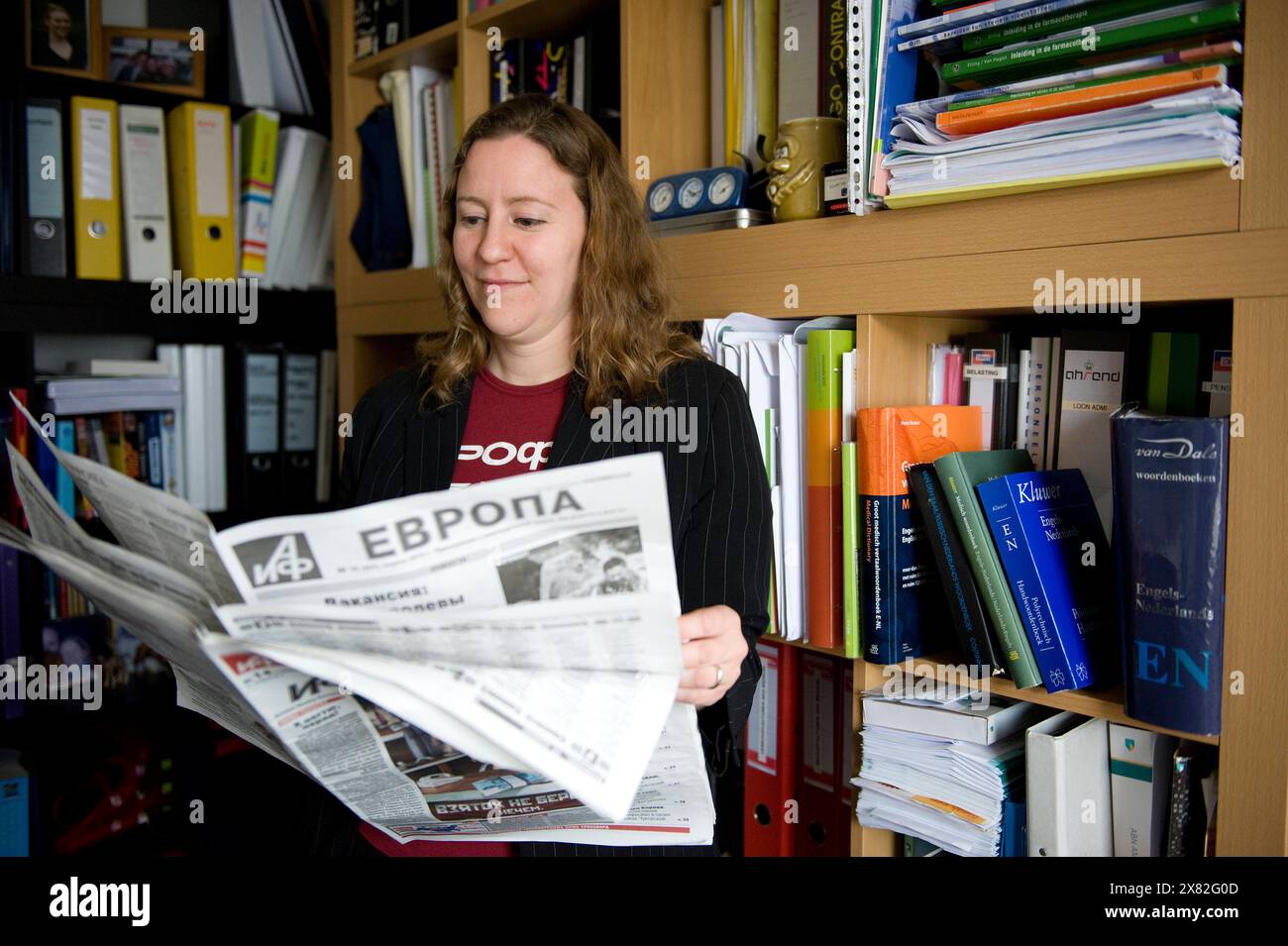 Frau, die Zeitung liest Junge Erwachsene Frau, die eine russische Zeitung liest, um sich auf dem Laufenden zu halten, da sie freiberuflich Russisch-Englisch-Übersetzerin ist. Tilburg, Niederlande. MRYES Tilburg Wolvegastraat Noord-Brabant Nederland Copyright: XGuidoxKoppesxPhotox Stockfoto