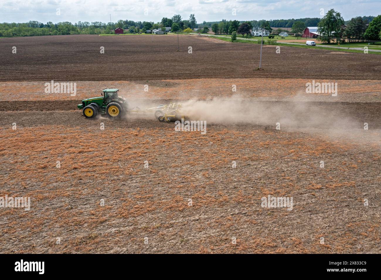 Hudson, Michigan – Eine Staubwolke bläst hinter den Traktor, während ein Landwirt sein Feld bebaut. Stockfoto