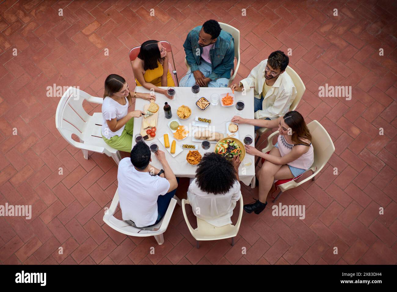 Blick von oben auf eine Versammlung von Menschen um einen Tisch mit Gläsern Wein und Essen Stockfoto