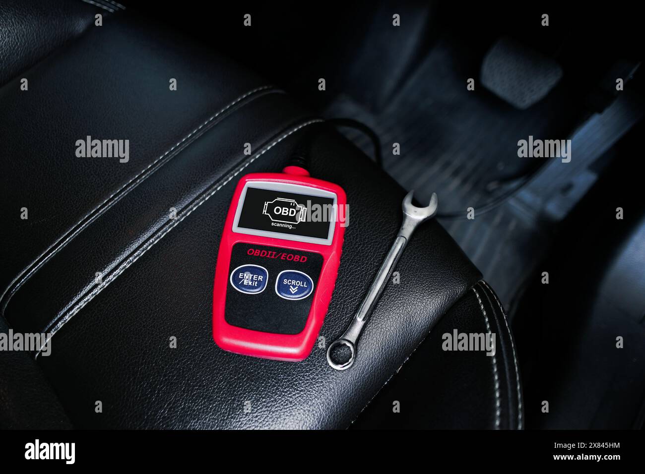 OBD2- oder OBD-Scanner und Schraubenschlüssel auf Ledersitz für die Motorsystemanalyse bis zur Befestigung des Motorsystems des Fahrzeugs , Servicekonzept für die Fahrzeugwartung Stockfoto
