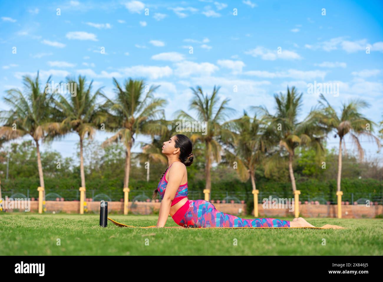 Junge indische Frau, die Cobra-Pose Bhujangasana Yoga-Pose in ihrem Garten macht. Sport, Wohlbefinden, Wellness, Workout, Meditation, psychische Gesundheit Conce Stockfoto