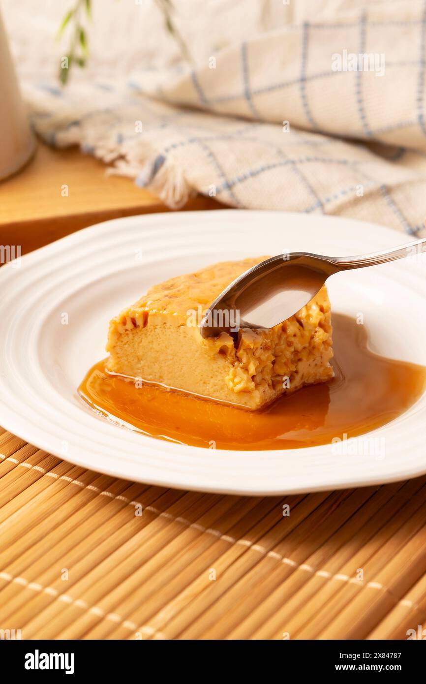 Hausgemachtes Flan Dessert, auch bekannt als Creme Caramel, Karamell Pudding oder Eierpudding, serviert auf weißem Teller auf Holztisch. Stockfoto