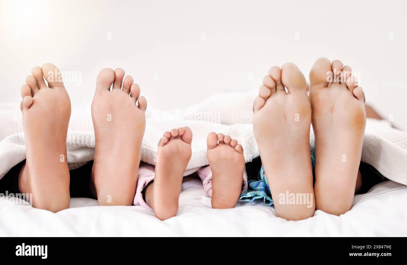 Mom, Dad und Kind mit Füßen im Bett, Ruhe, Frieden und Morgen, die sich in der Wohnung verbinden. Entspannen Sie sich, zu Hause und Eltern schlafen mit Kind Stockfoto