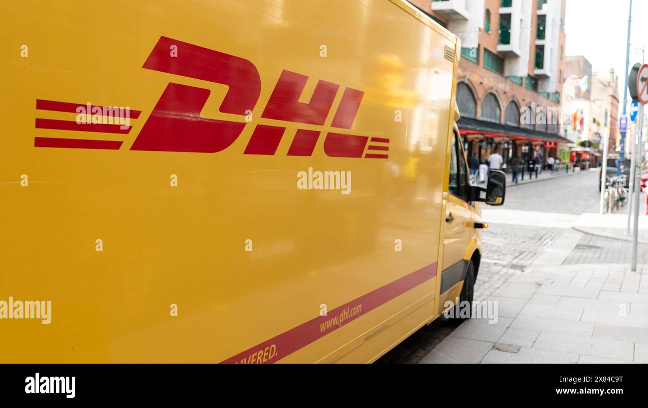 DUBLIN, IRLAND - 26. MÄRZ 2023: Gelber DHL-Lkw parkt am Straßenrand mit heller Fahrzeugbeleuchtung Stockfoto