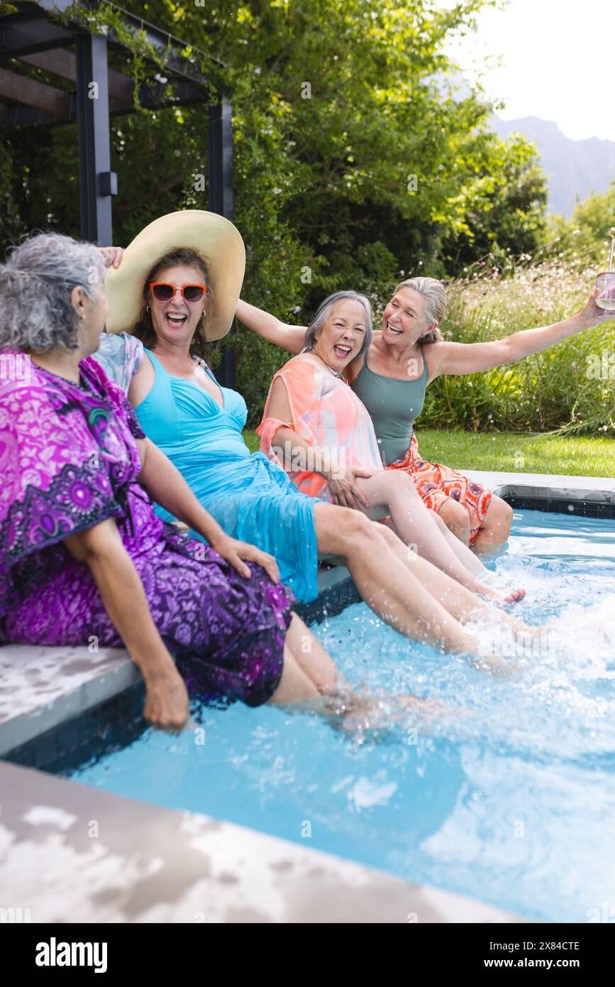 Verschiedene ältere Freundinnen lachen draußen am Pool Stockfoto