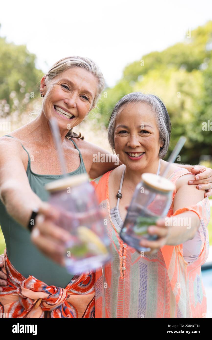 Draußen, verschiedene ältere Freundinnen, die Getränke halten, vor Freude lächeln Stockfoto