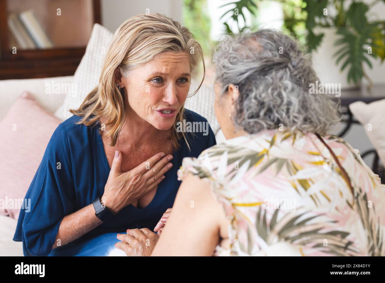Verschiedene ältere Freundinnen diskutieren zu Hause und zeigen Besorgnis Stockfoto