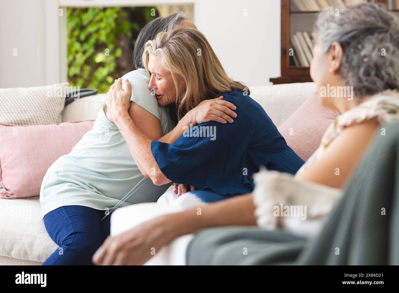 Verschiedene ältere Freundinnen trösten sich zuhause auf der Couch Stockfoto