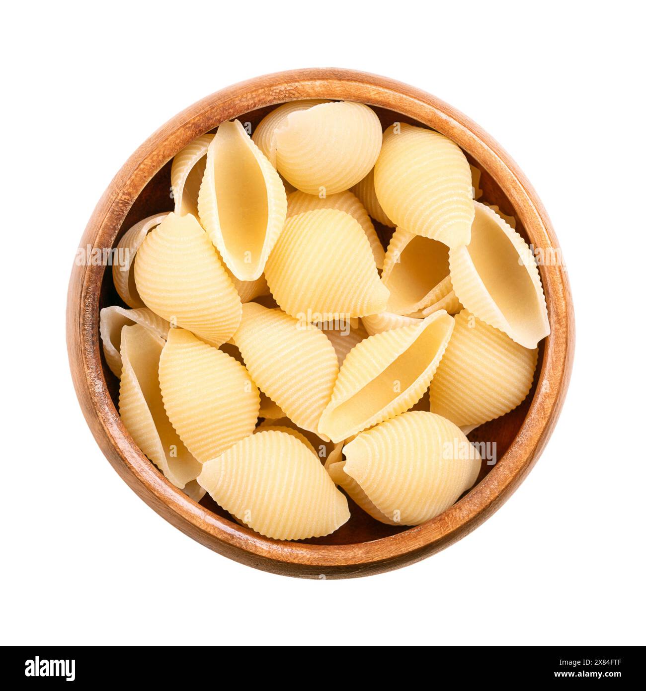 Conchiglie Rigate, schalenförmige und gefurchte italienische Pasta in einer Holzschale. Ungekochte Hartweizengrißnudeln. Nahaufnahme, von oben. Stockfoto