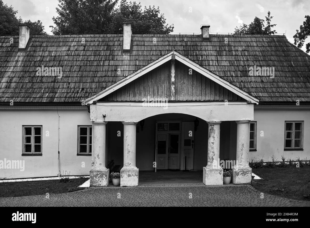 Eingang mit Steinsäulen zu einem historischen Herrenhaus in der Stadt Zloty Potok, Polen, monochrom Stockfoto