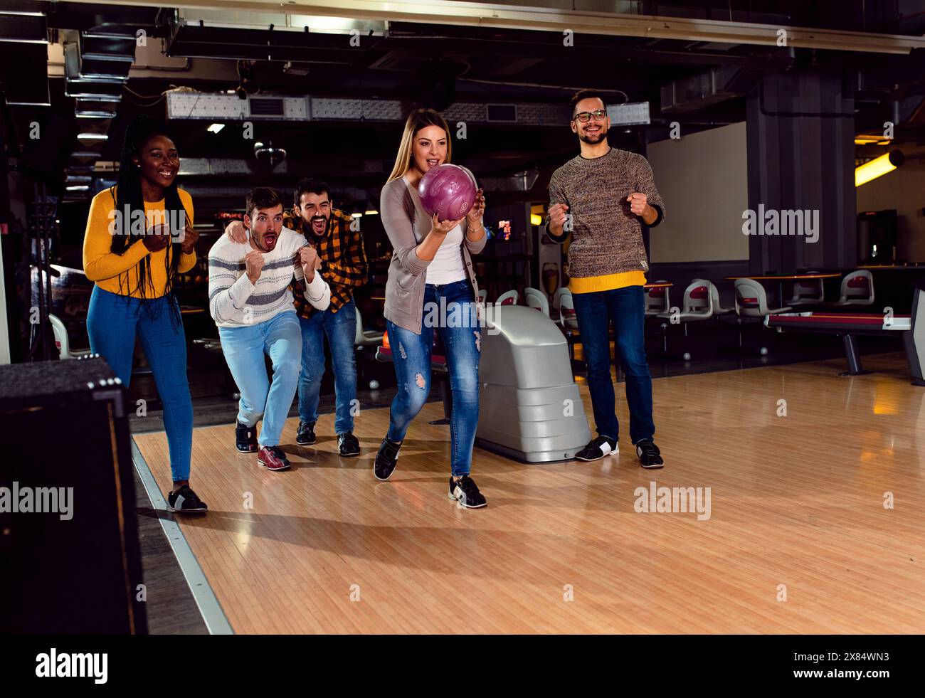 Eine Gruppe von Freunden genießt die gemeinsame Zeit, lacht und jubelt beim Bowling im Club. Stockfoto