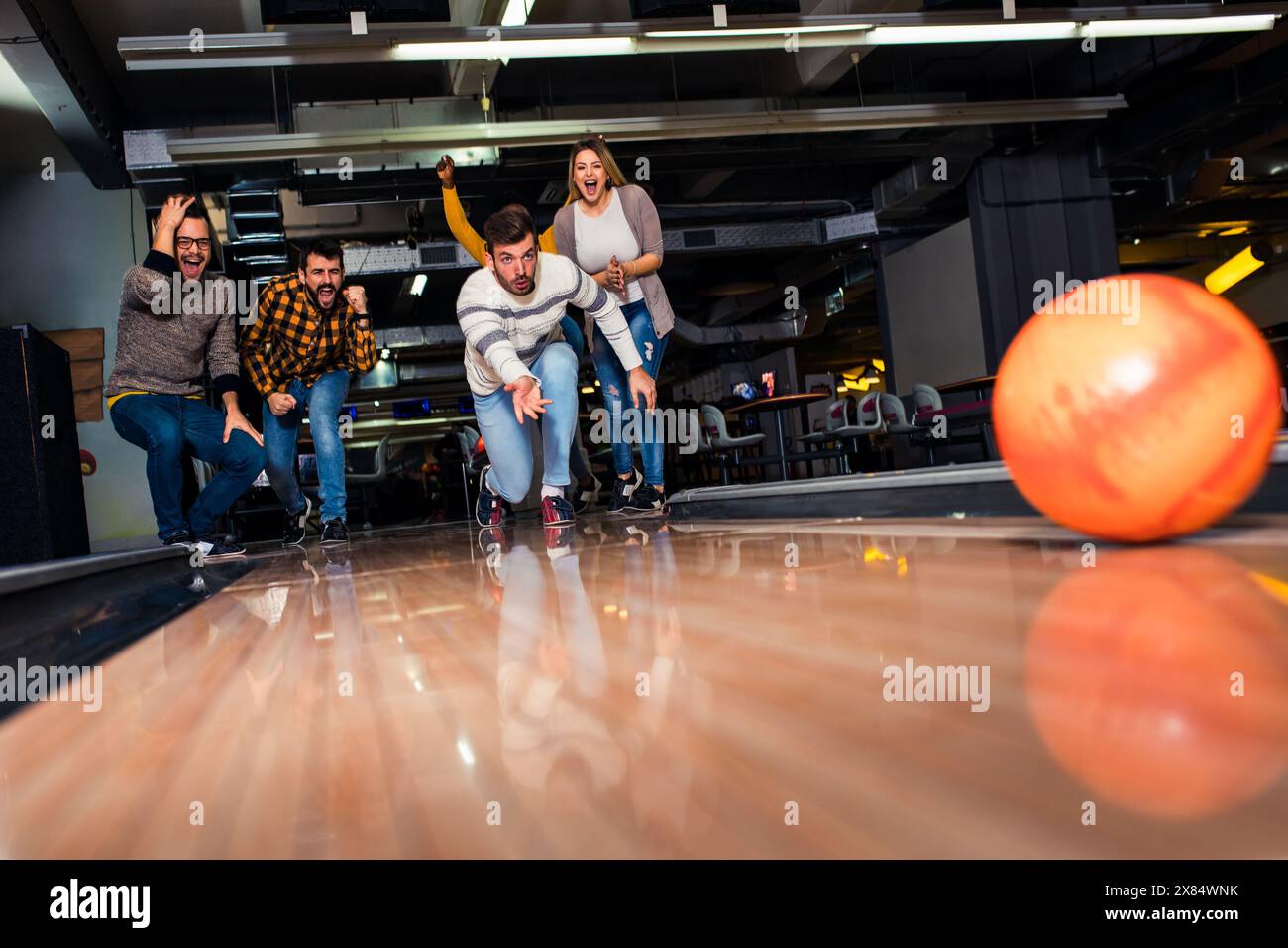 Eine Gruppe von Freunden genießt die gemeinsame Zeit, lacht und jubelt beim Bowling im Club. Stockfoto
